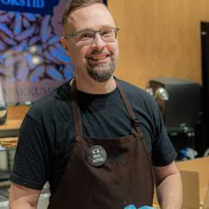 Rein on Tartu Kaubamaja Matsimokas töötanud juba… kas tõesti 10 aastat!? 😄 Aeg lendab, kui teha asja südamega. Ta on meie kõige staažikam müüja – elav legend, keda tullakse otsima nimepidi. 

Reinul on haruldane supervõime – ta näeb juba üle prillide ära, mille järele sa tulid. 👀 Piisab ühest pilgust, poolikust lausest või kergest kõhklusest ja juba sätib ta leti peale just need õiged hõrgutised. “Midagi grillile?” – Rein juba teab, millist. “Külalised tulemas?” – tal on plaan valmis enne, kui sa jõuad muretseda.

Tema leti ees lookleb tihti järjekord. Ja mitte niisama. Reinu karisma, energia ja siiras hoolimine mõjuvad magnetina. Ta tunneb püsikliente, mäletab nende lemmikuid ja uurib alati, kuidas eelmine soovitus välja kukkus. See pole lihtsalt ost – see on väike kohtumine, kust lahkutakse hea tuju ja hea kraamiga.

Ja võib-olla polegi ime, et Rein inimesi nii hästi “loeb”. Vabal ajal sukeldub ta hoopis fantaasiamaailma – mängib DnD-d, osaleb LARP-il ning ehitab oma kätega butafooria- ja cosplay-stiilis originaalkostüüme. 🎭⚔️ Detailid, karakter ja rolli sisse elamine on talle omased nii hobides kui ka leti taga. Kui keegi oskab hetkega õige rolli võtta – olgu selleks grillimeister, peolaua päästja või maitsete teejuht – siis on see Rein.

Rein armastab oma tööd ning see paistab igas liigutuses. Ta on kiire, vaimukas, tempokas ja alati heas hoos – isegi siis, kui päev on pikk ja tempo selline, et iga sammulugeja võiks tema üle uhkust tunda. 😉

Reinu lemmiktoode on vaieldamatult peekon 🥓. “Ainuüksi peekoni lõhn toob värvid päeva tagasi,” mõtiskleb ta ja nendib, et kui üks 🍎 päevas hoiab arsti eemale, siis üks peekon päevas hoiab tusatuju ära! 😄

Kui satud Tartu Kaubamaja Matsimokasse ja näed järjekorda, siis tea – suure tõenäosusega on leti taga Rein. Astu julgelt sappa. Legend teab, mida sa täna õhtul sööd. 🥩🔥

Tartu Kaubamaja





